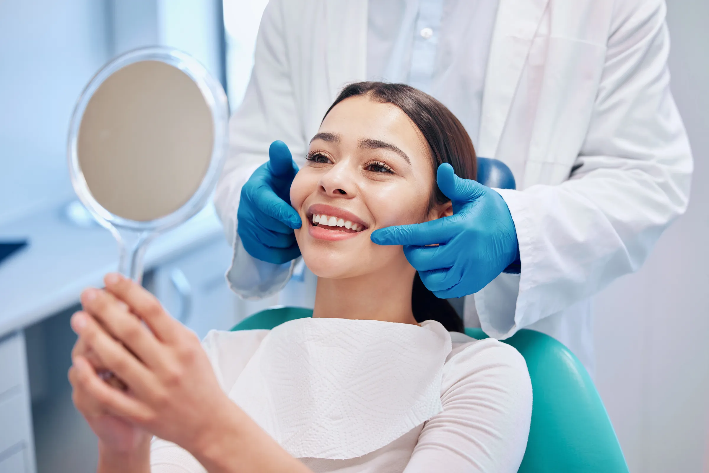 A patient reviewing her smile in a mirror after treatment