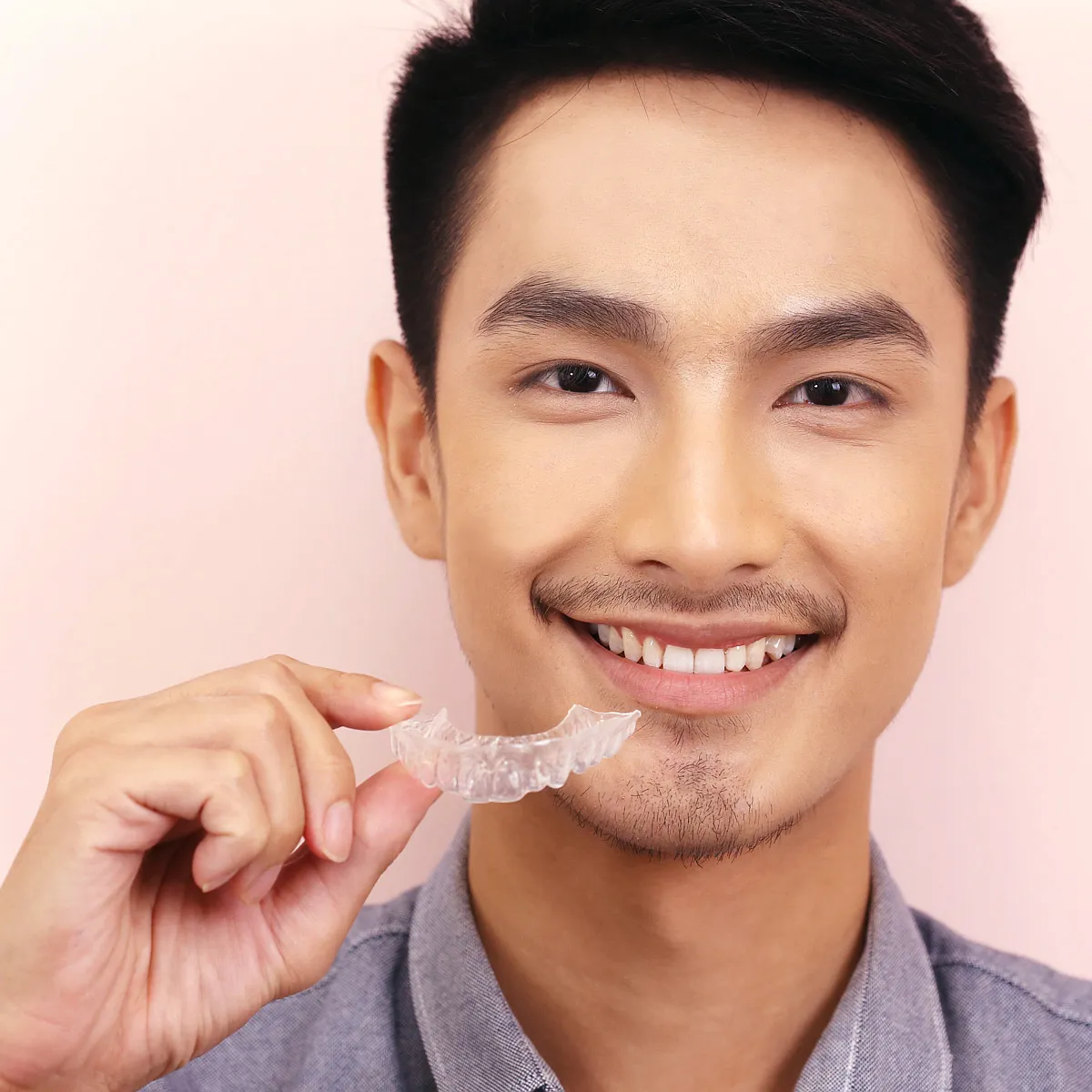 A teenage patient holding a clear aligner tray.