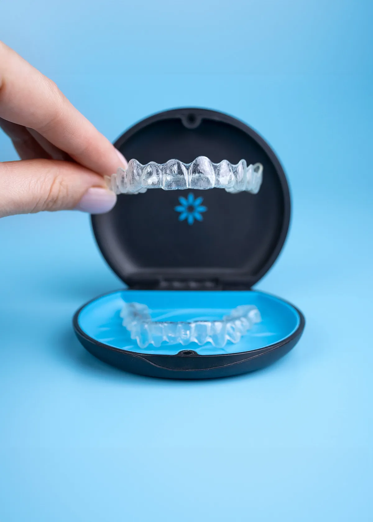 Patient smiling while holding a clear aligner case