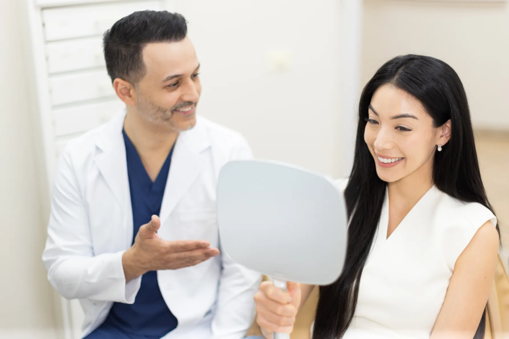 A dentist showing a patient her smile in a hand mirror